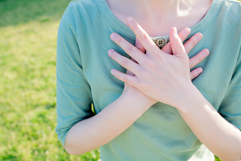 Woman with hands crossed over chest in peace and relief.